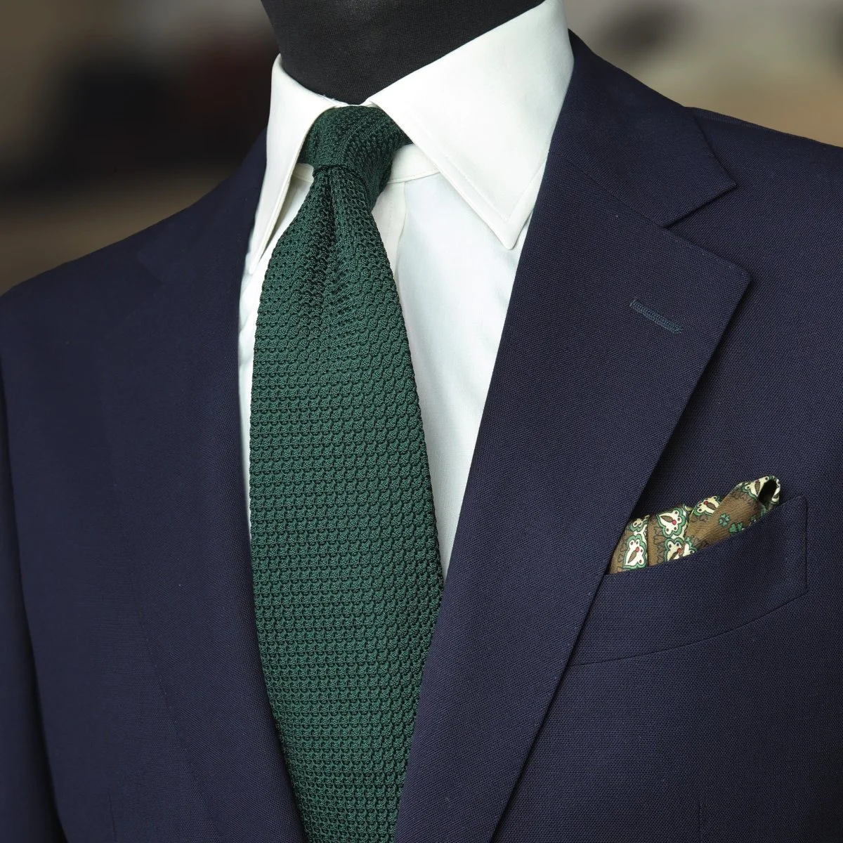 Žalias kaklaraištis, balti marškiniai ir mėlynas kostiumas